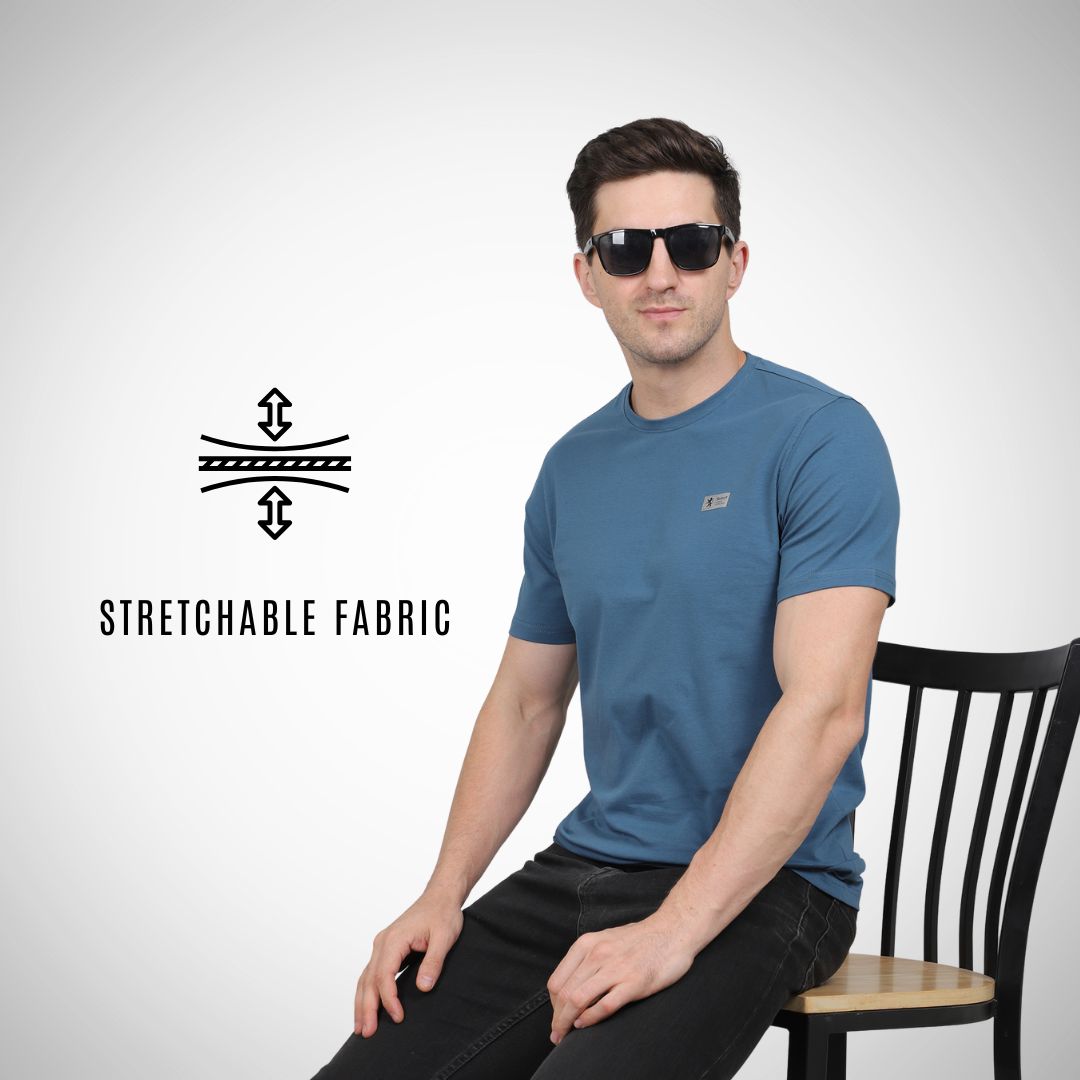 Man wearing a blue t-shirt sitting on a chair with 'Stretchable Fabric' text and logo.